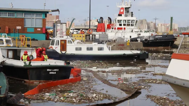 An African port. A large amount of solid waste floats on the surface of the water around the ships.