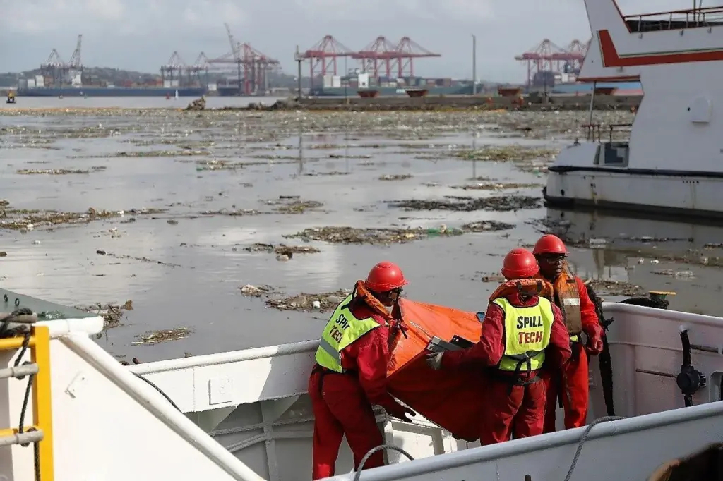 A team of workers in a port clearing waste from the water.