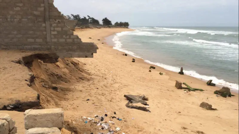 Collapsed buildings on the Togo coast, with a brick wall undercut by beach erosion.