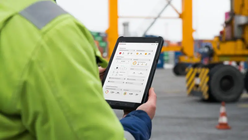 yourKONECRANES displayed on a tablet being held by a man in a high-vis jacket