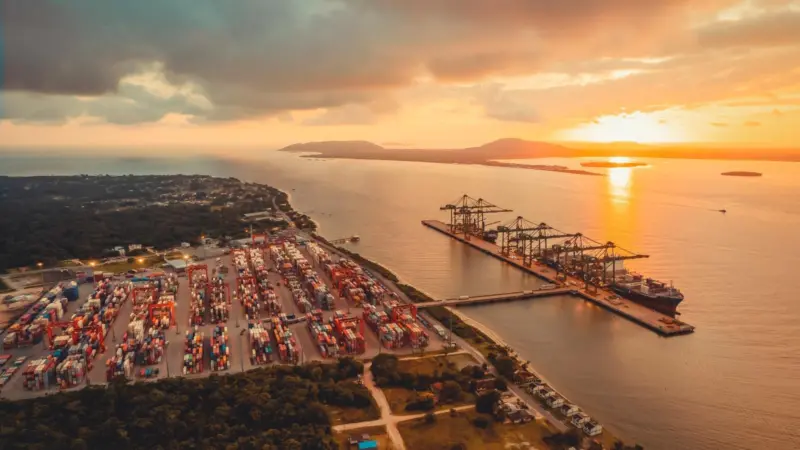 The photo shows a sunset drenched overhead shot of Porto Itapoá in Brazil