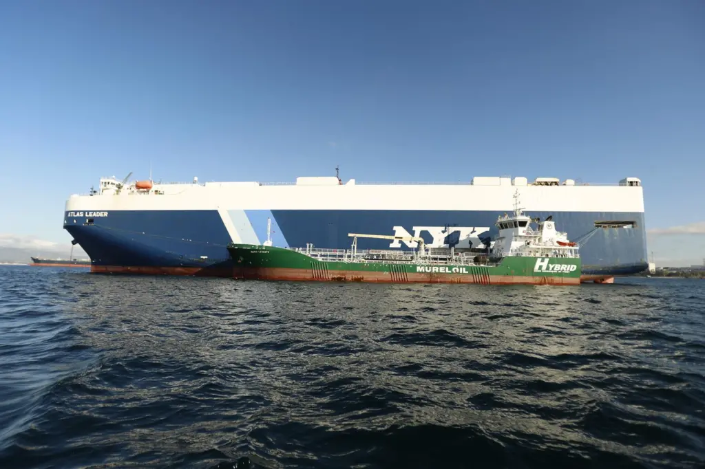 The picture shows NYK Line’s Atlas Leader being bunkered with biofuels by Cepsa’s electric port hybrid barge, Bahía Levante