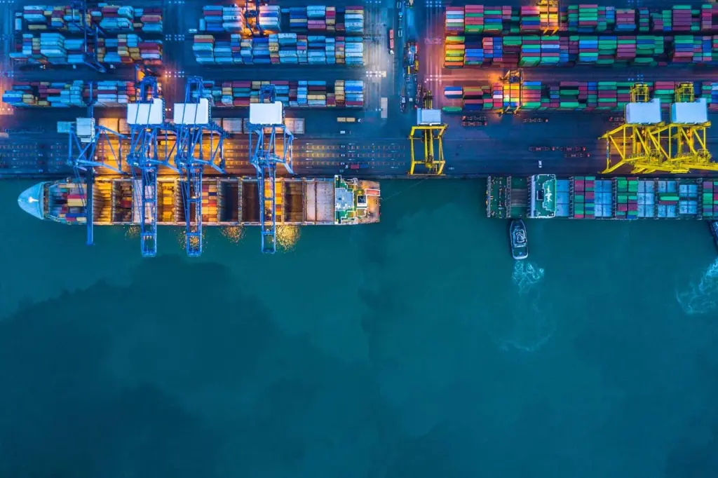 The image shows vessels berthed at a terminal with a container yard in the background