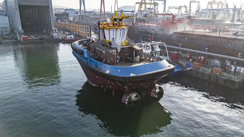 A fully electric tug alongside a dock
