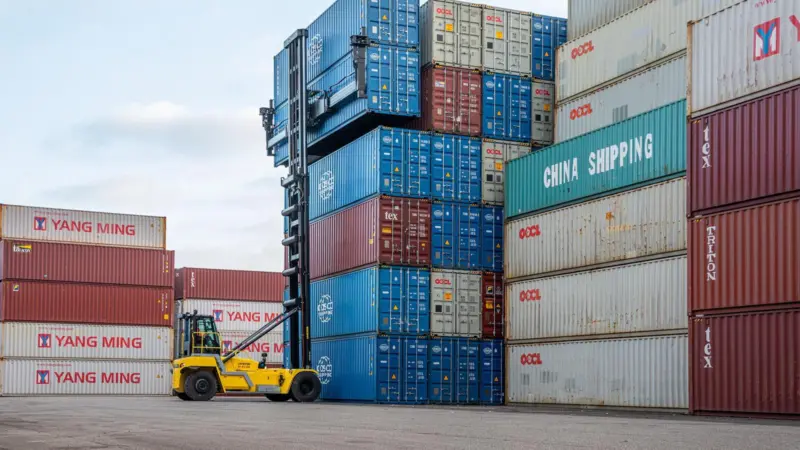The image shows a Hyster electric container handler stacking boxes