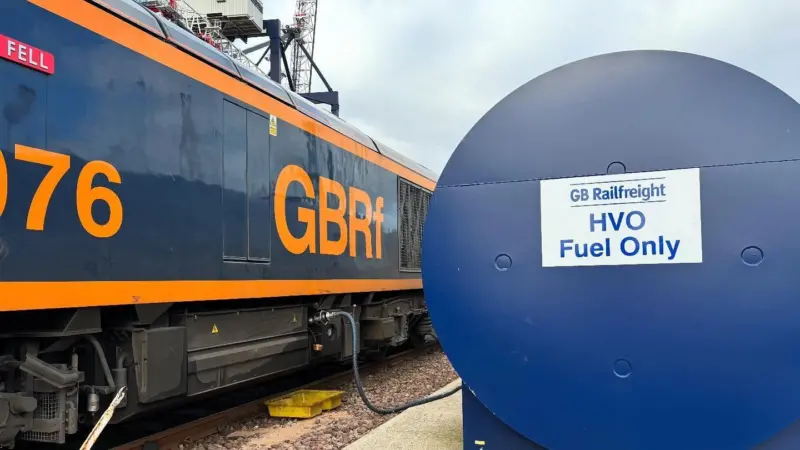 The image shows a GB Railfreight train with HVO storage in the foreground