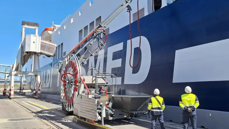 The image shows two operators checking the OPS cabling management system to ensure the connection to the ship quayside
