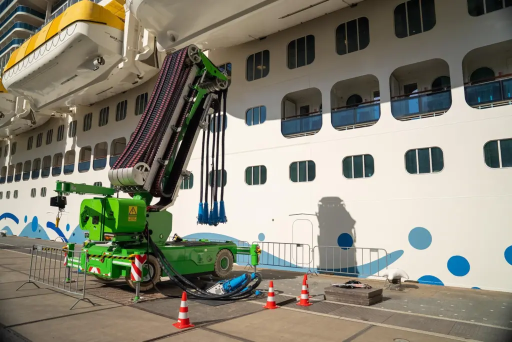The image shows a cruise vessel plugged into shore power on the quayside