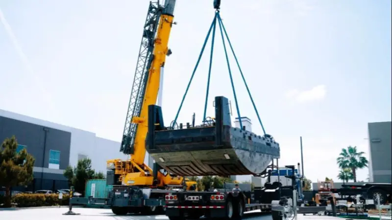 The image shows the 26 foot electric tug being lifted during construction