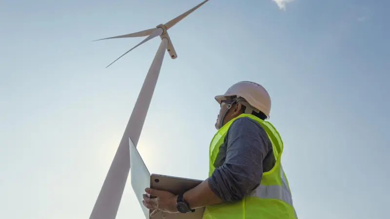 engineer using a laptop near wind turbine