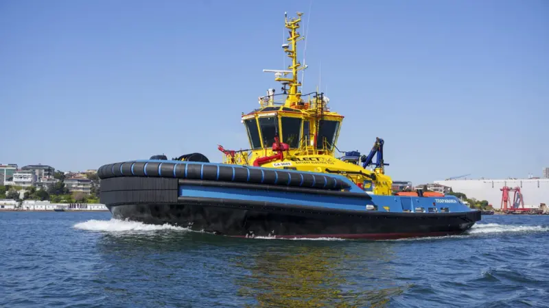 The picture shows a SAAM electric tug on the water