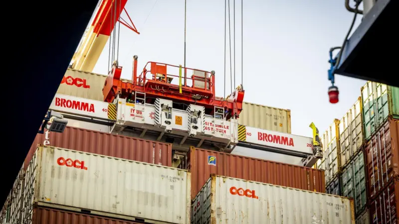 The image shows a Bromma electric STS spreader in action on the quayside