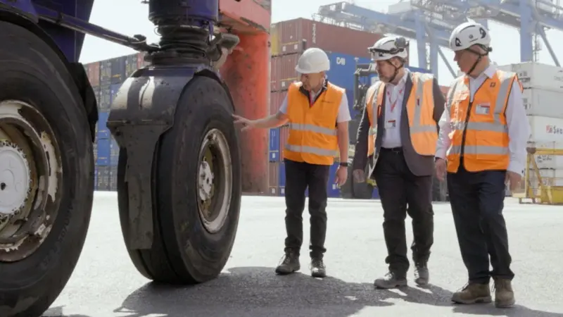 The image shows a Continental tyre being examined by operators on the quayside