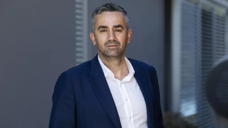 A picture of Phillipos Ioulianou dressed in a blue suit smiling for the camera
