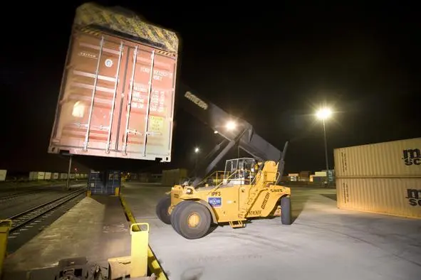An empty container being transported with heavy equipment
