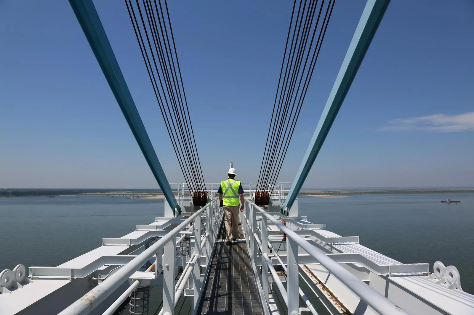 A worker walking across a suspended bridge.