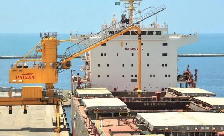 A pneumatic unloader over a docked cargo ship.