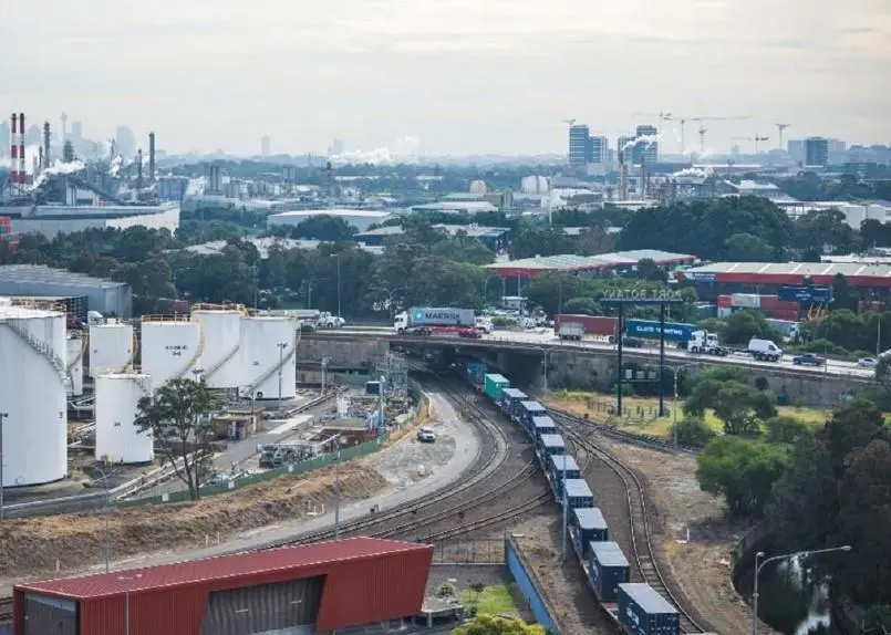 A rail shuttle entering Port Botany, with the Sydney city skyline in the distance