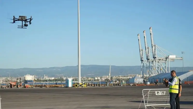 The picture shows a drone being flown by an operator at the Port of Tarragona