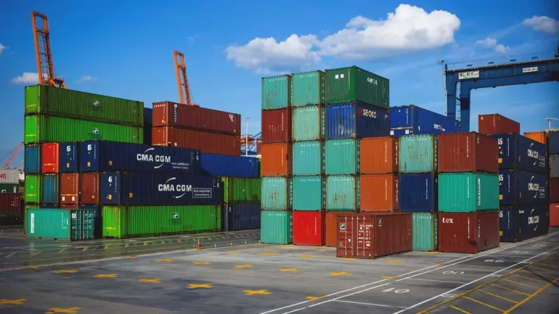An image of colourful shipping containers stacked on a quayside