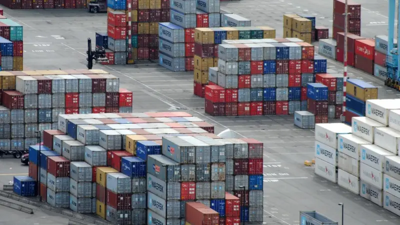The image shows hundreds of colourful shipping containers arranged in a yard