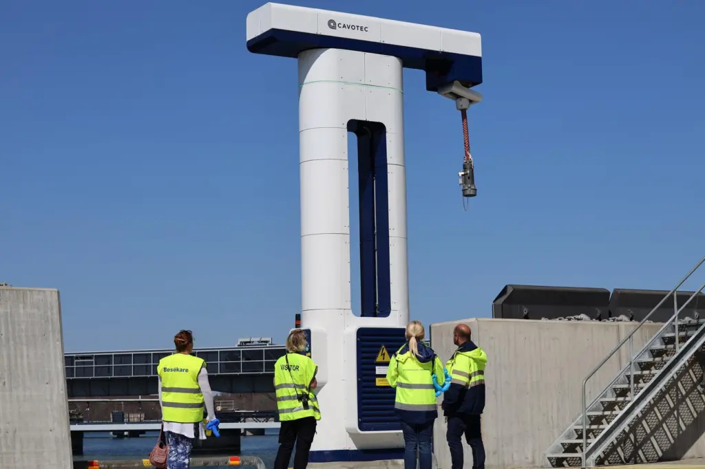 onshore power connection at the Port of Kapellskär in Stockholm with four workers in hi-viz standing at its base