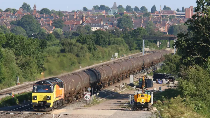 Colas Rail Freight Class 70 811 on a rail track with roofs in the distance