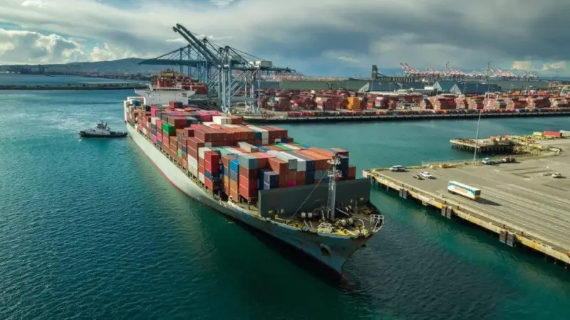 A container ship at port with a crane behind