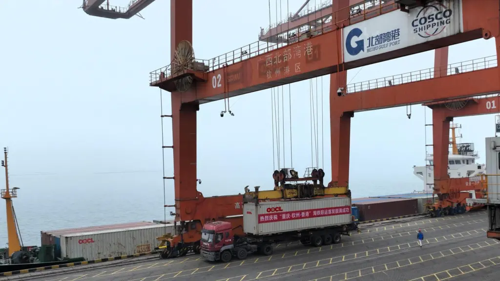 An OOCL truck sits beneath a large crane as its container is loaded
