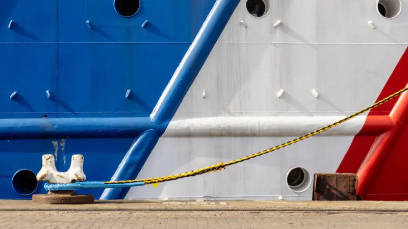 A close-up of a moored ship in red, white and blue