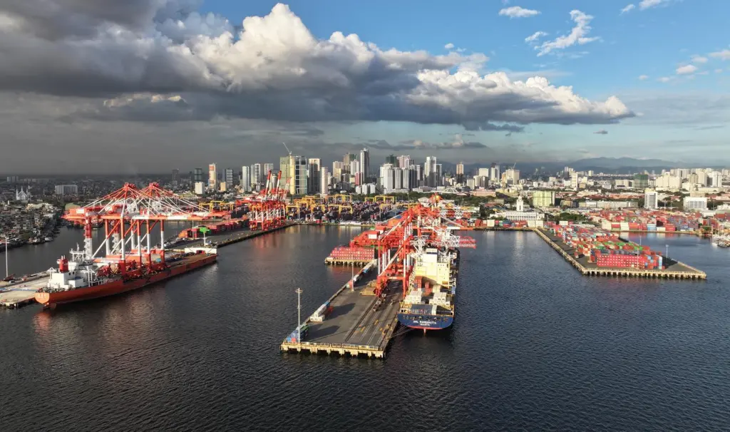 Manila South Harbour, Philippines, showing ships portside, a number of ship-to-shore cranes and high rise buildings in the background