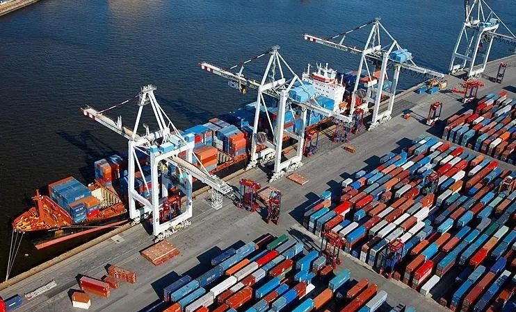 Aerial shot of a container ship at dock at the Port of Hamburg with four ship-to-shore cranes and containers dockside
