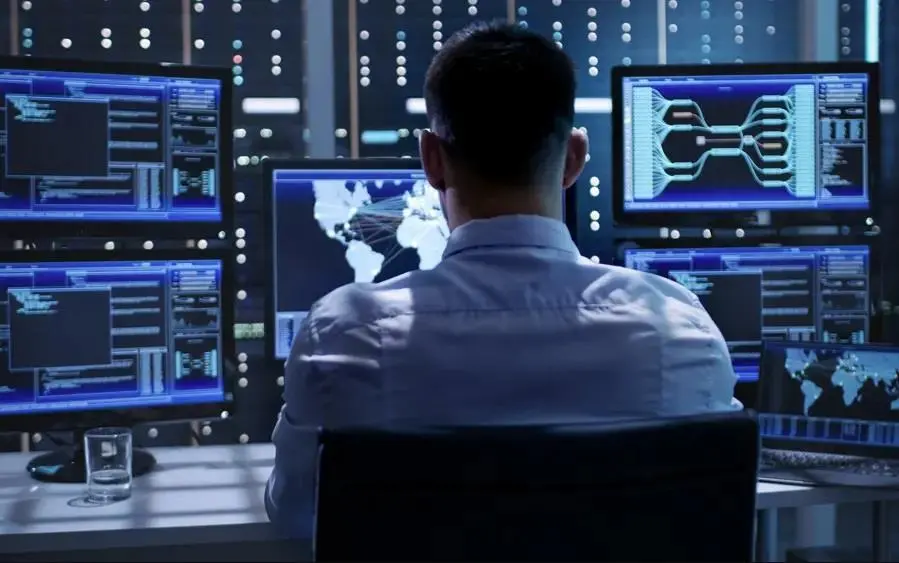 Man looking at five computer screens