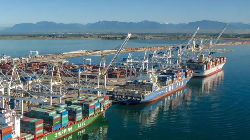 Three container ships at dock in Deltaport, Canada with cranes shoreside