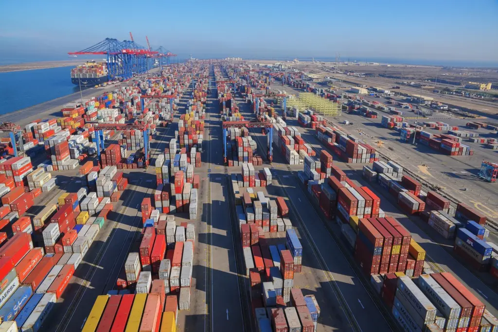 Containers at the Suez Canal Container Terminal with a shit and cranes to the left background