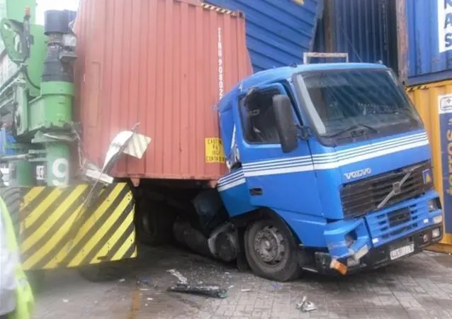 A blue Volvo lorry squashed underneath collapsed shipping containers